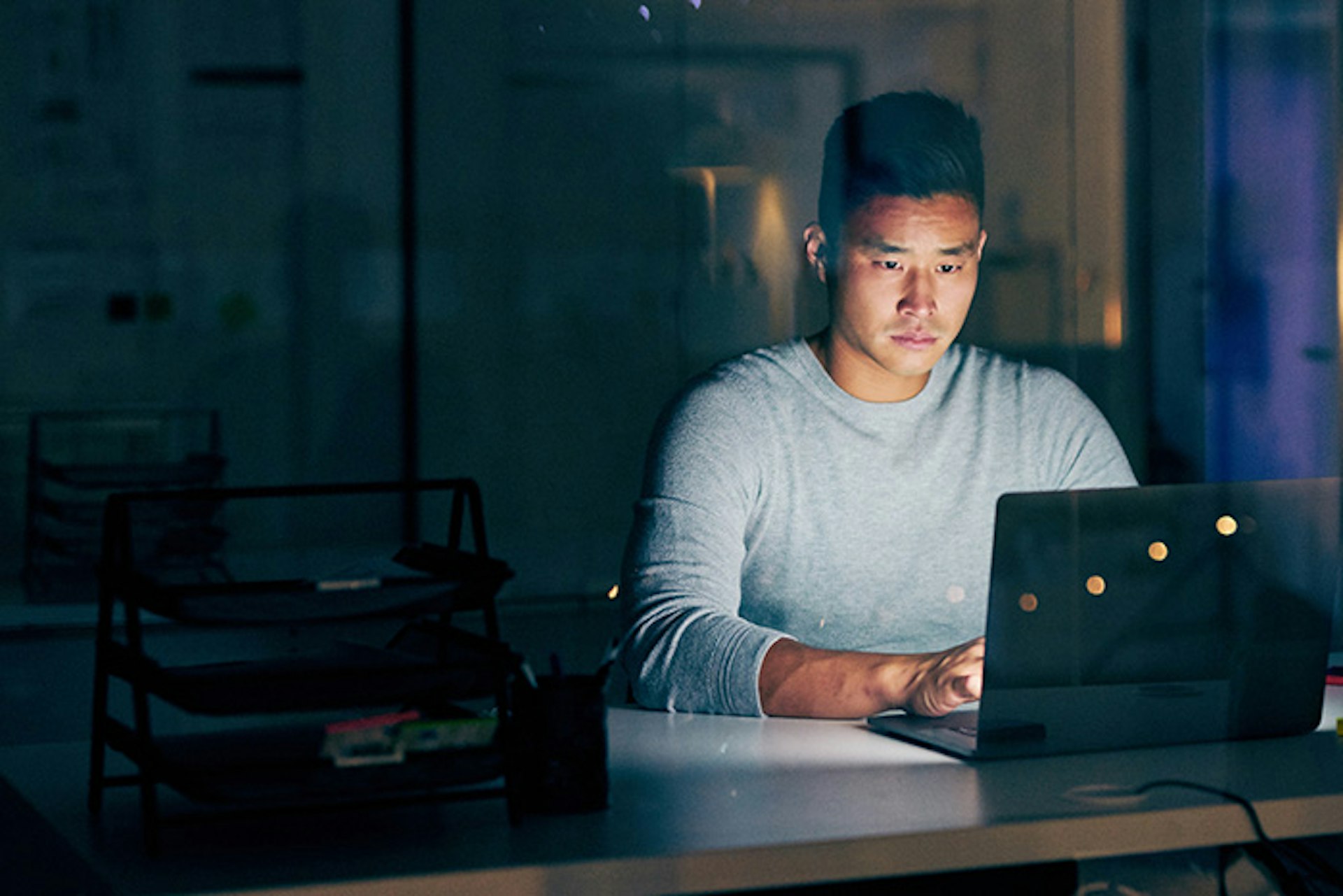 Man illuminated by laptop in a dark room